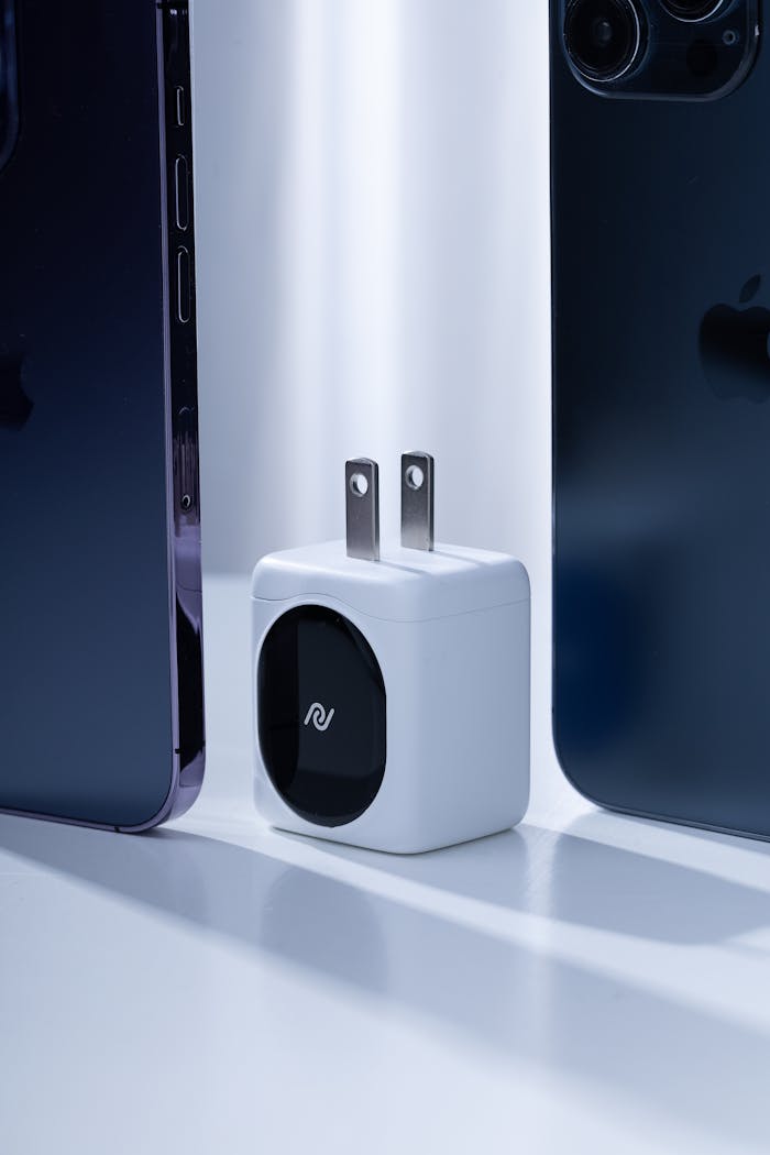 Compact modern charger placed between two dark smartphones, highlighting technology innovation.